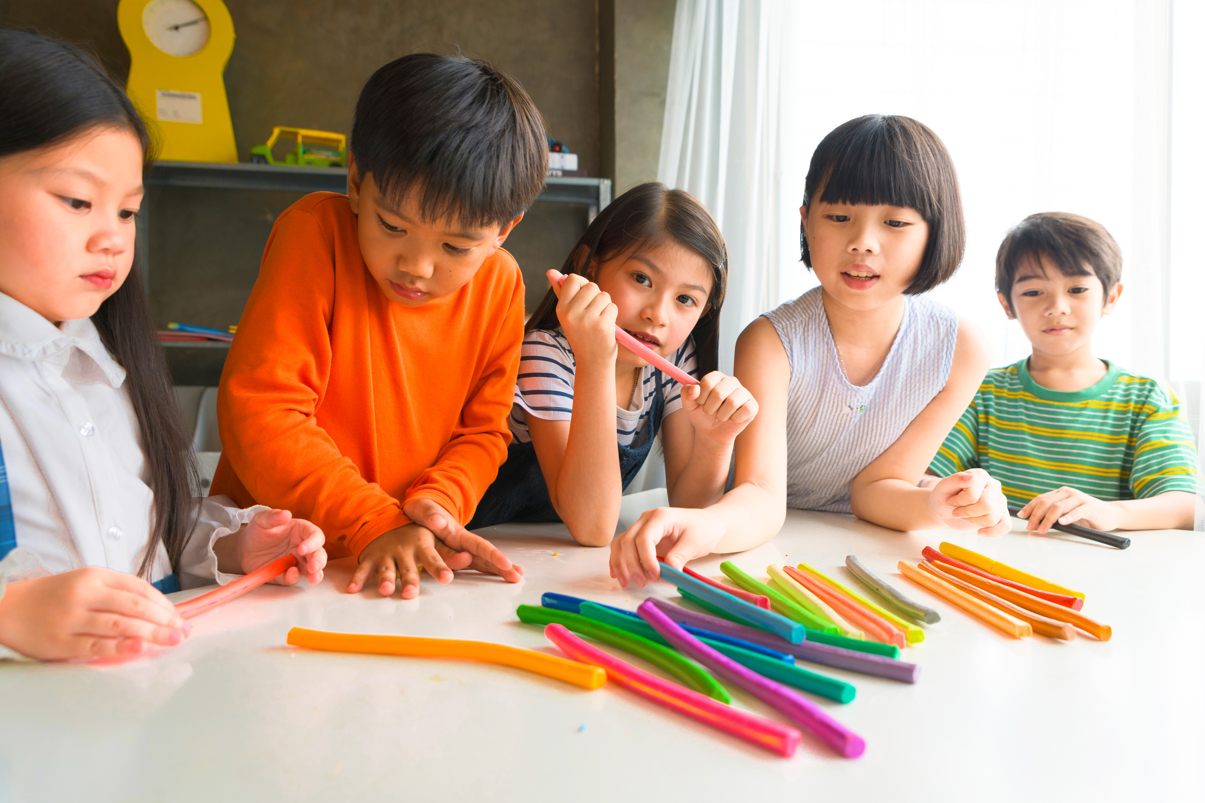 Asian kids playing with play colorful clay at home or kindergarten or playschool